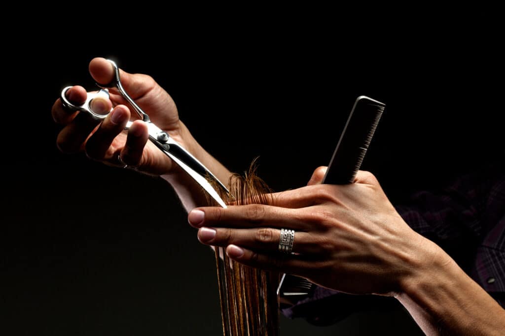 A close-up of hairdresser's hands cutting hair